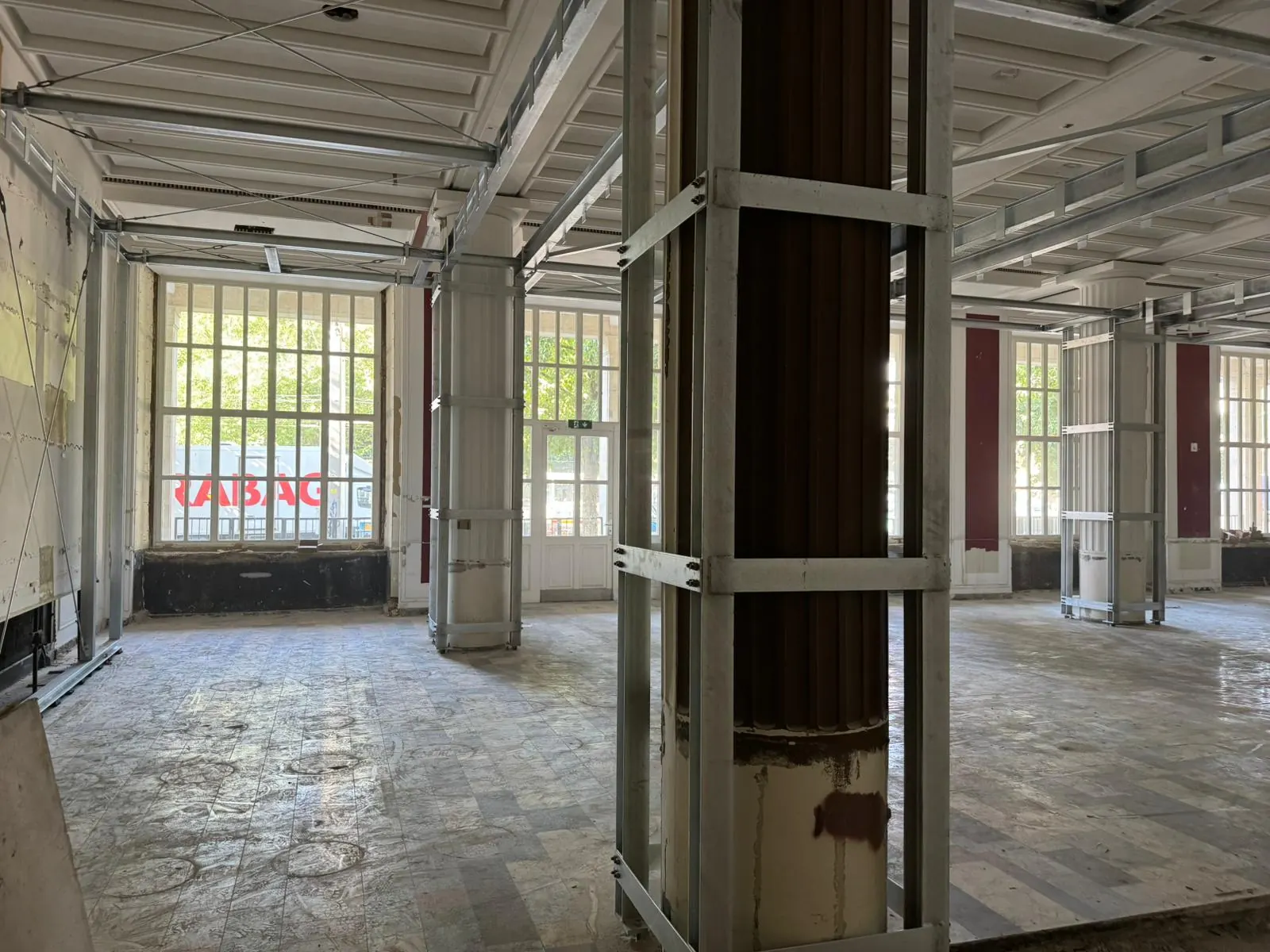 Historischer Saal mit hohen Sprossenfenstern und neuer Stahlkonstruktion